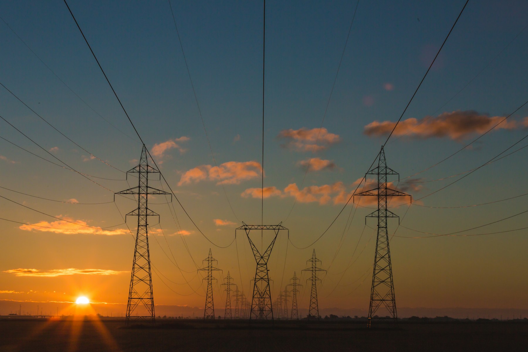 Transmission towers at sunset, representing the energy grid CrewVolt staffs.